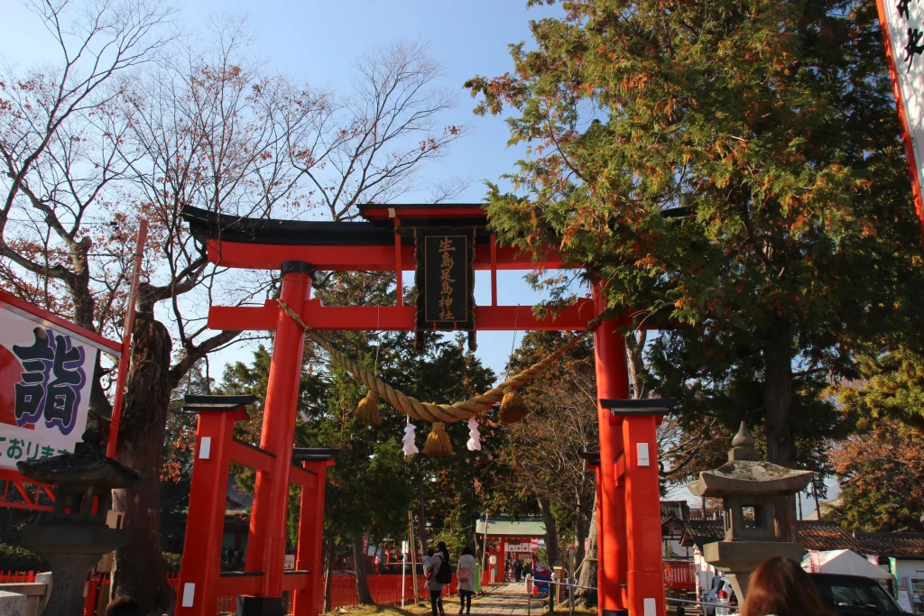 青空に映える朱塗りの生島足島神社・東大鳥居と大きなしめ縄の風景