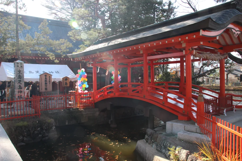 神池の水面に朱色が美しく映える生島足島神社の屋根付き御神橋