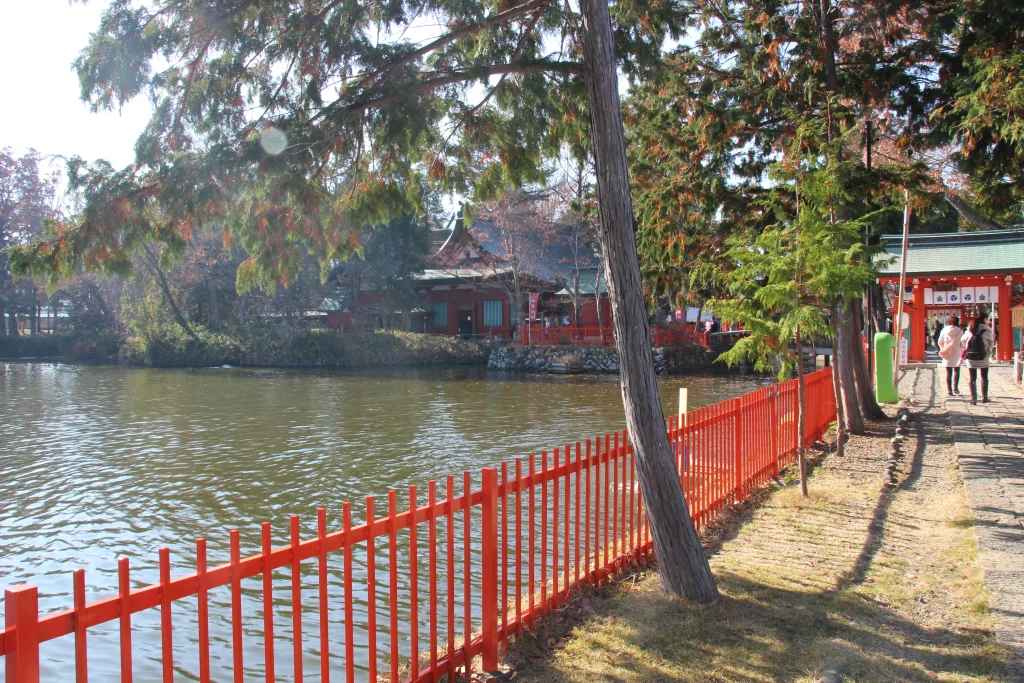 生島足島神社の神池と朱塗りの玉垣、奥に佇む池心の宮（社殿）の景観