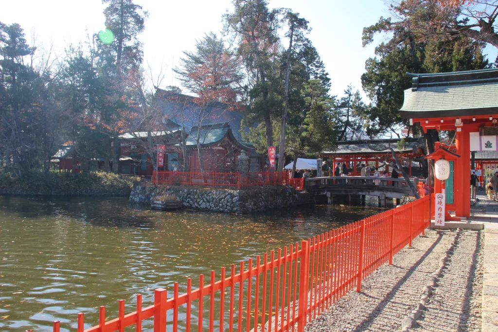 生島足島神社の神池を囲む朱色の玉垣と神門へと続く静かな石畳の参道