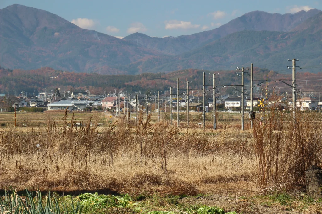 信州塩田平を走る単線の線路と背後に広がる独鈷山の美しい山岳景観