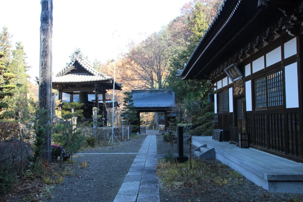本堂の板張り廊下から山門や鐘楼、石畳の参道を見渡す情緒ある境内の風景