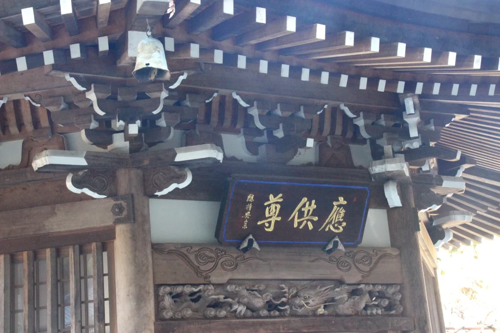 精巧な組物と白漆喰壁が美しい羅漢堂の軒下と「應供尊」の扁額