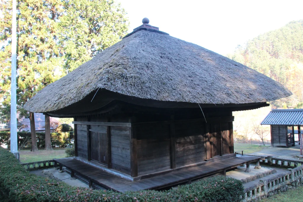 青空と周囲の樹木に囲まれた中禅寺薬師堂の美しい斜めアングル全景