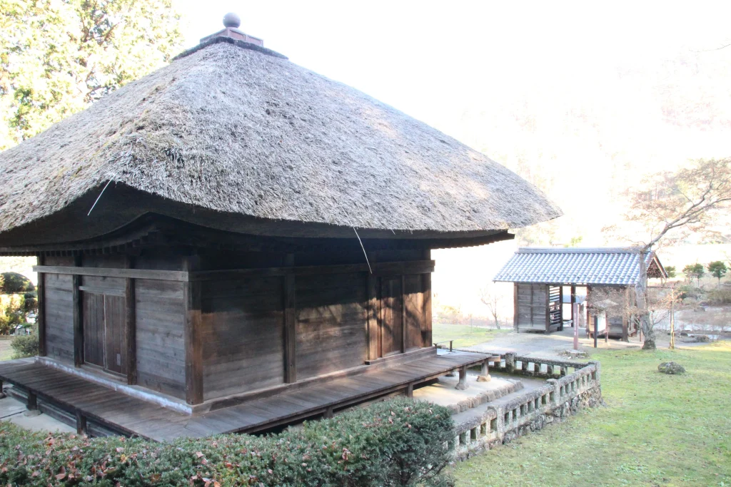 薬師堂の板壁と回廊から木々が広がる中禅寺境内の奥へ続く散策路