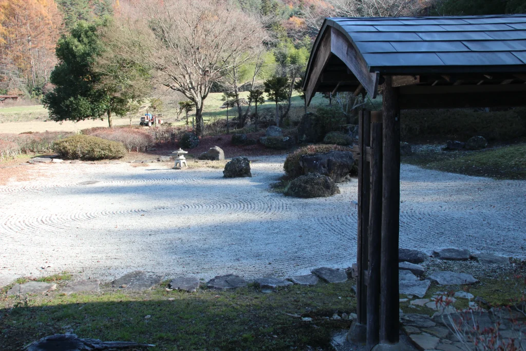 中禅寺の枯山水庭園を風情ある門の屋根越しに望む。上田市観光で訪れたい、侘び寂びを感じる日本庭園の風景です。