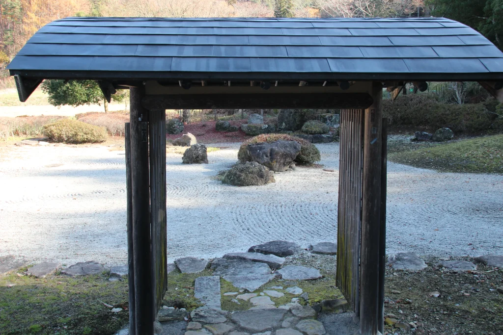門を額縁に見立てた、絵画のように美しい中禅寺の枯山水。石畳から覗く白砂と石組が計算された美を演出します。