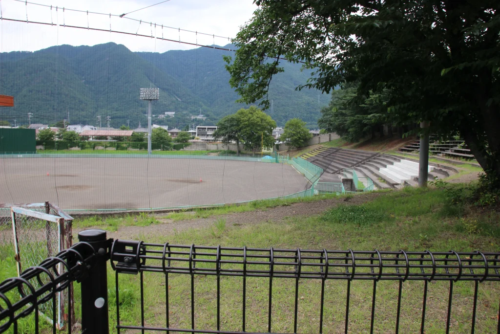 青々とした緑と山々に囲まれた上田城跡公園野球場のグラウンドと観客席