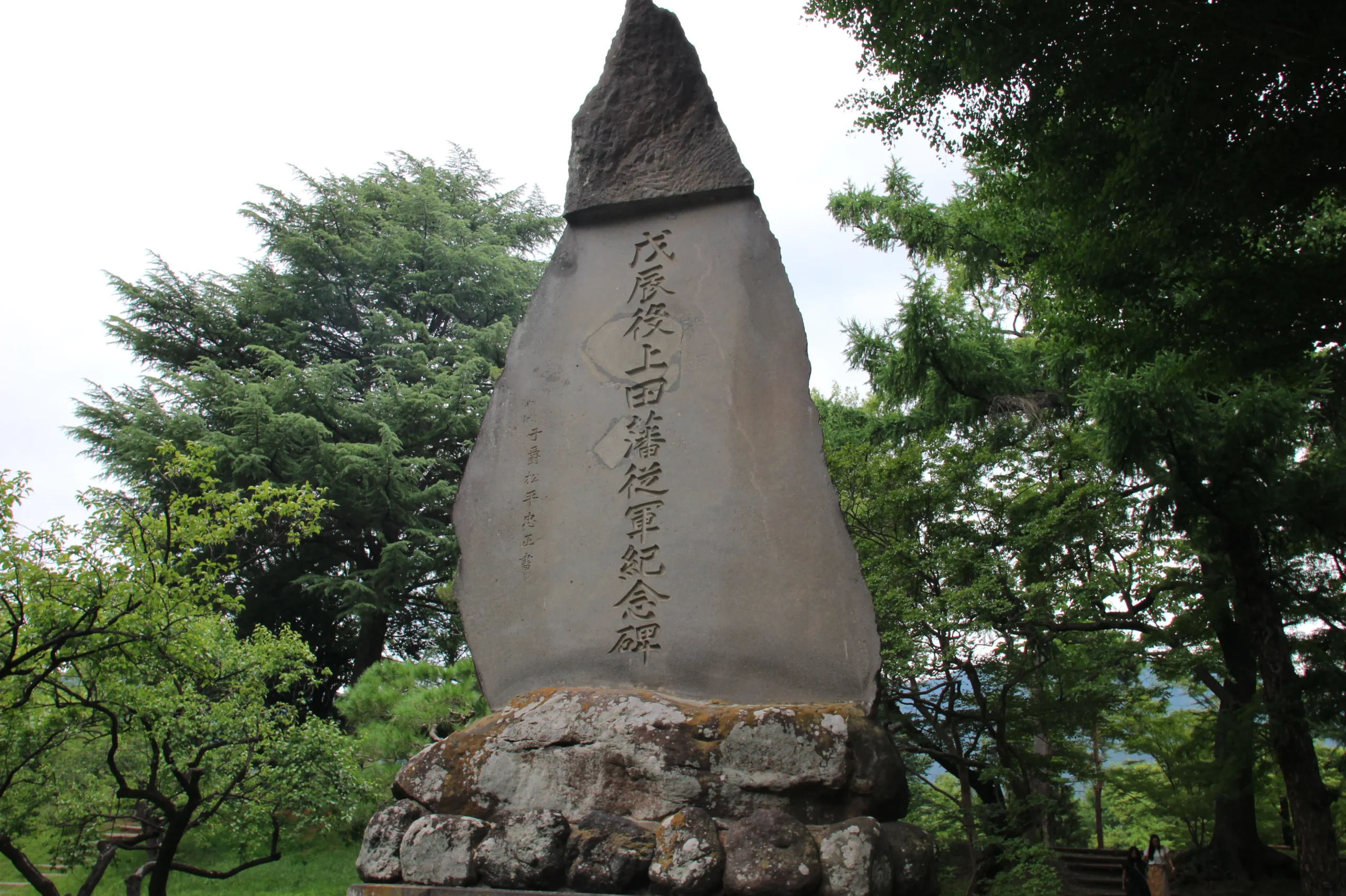緑深い木々の木陰に建つ歴史的な「戊辰役上田藩従軍紀念碑」の石碑