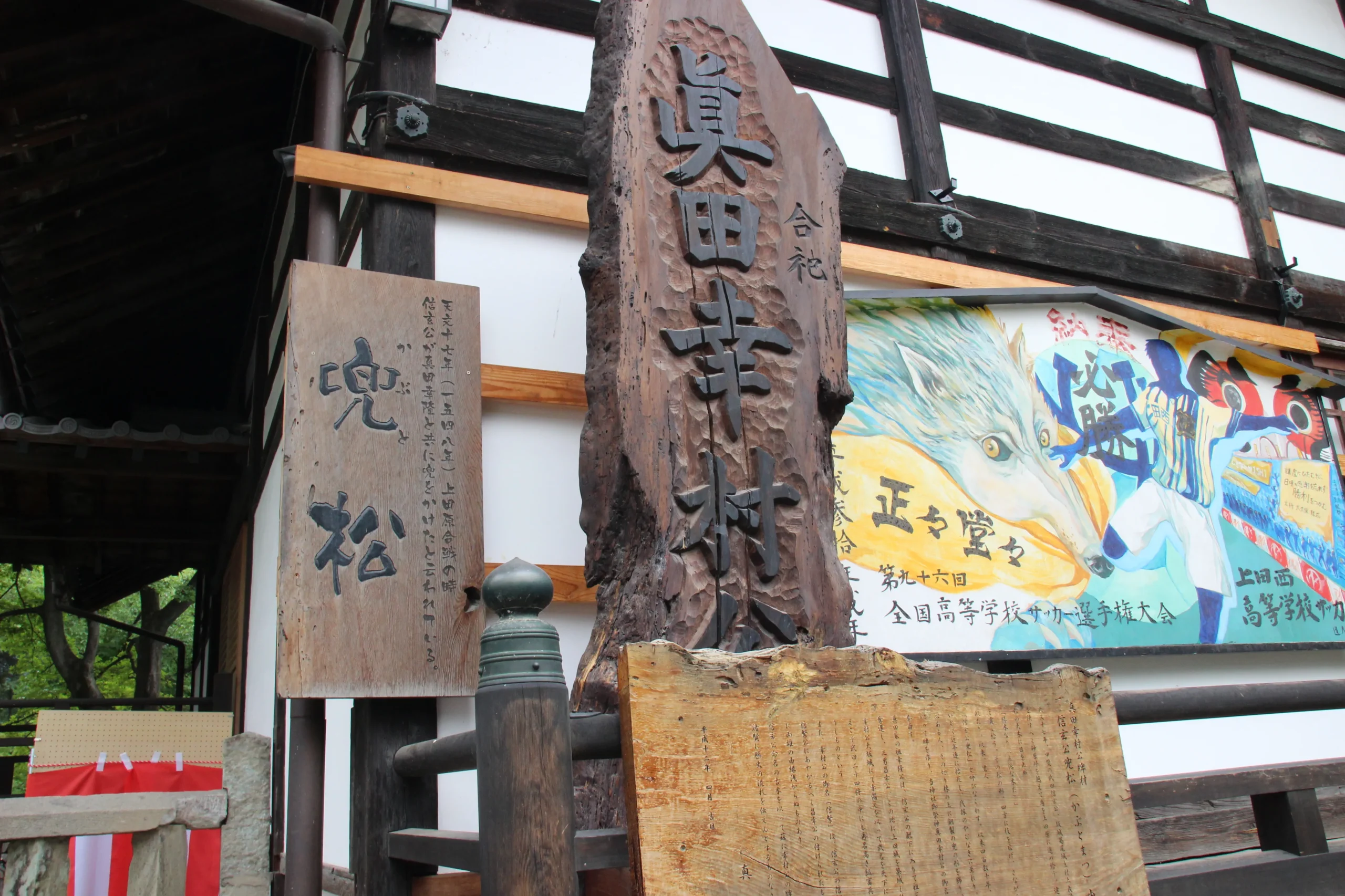 「真田幸村公」と刻まれた巨大な木製記念碑と兜松の解説板