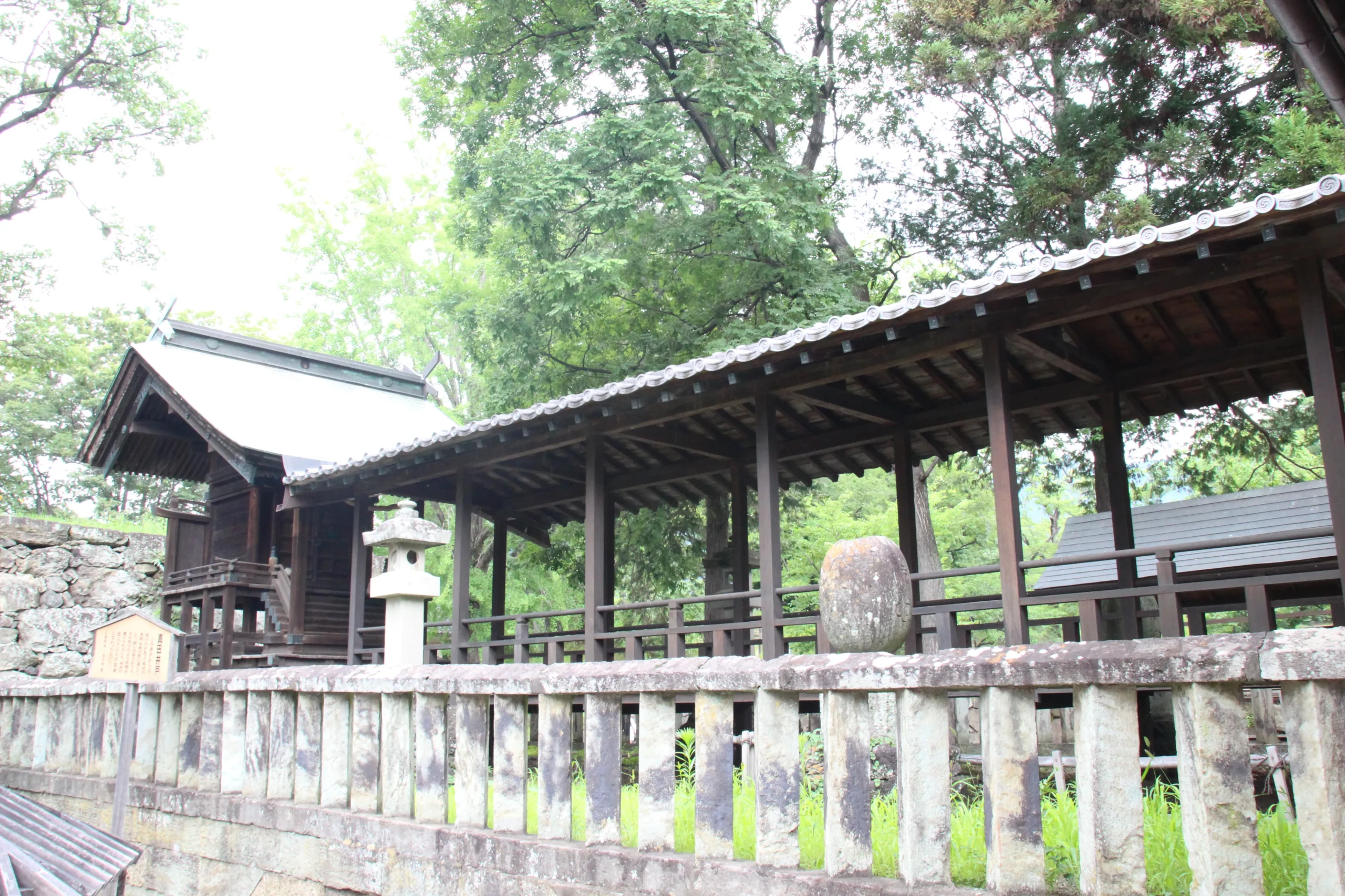 眞田神社の境内奥にある美しい木造の回廊と歴史的な石垣・石灯籠