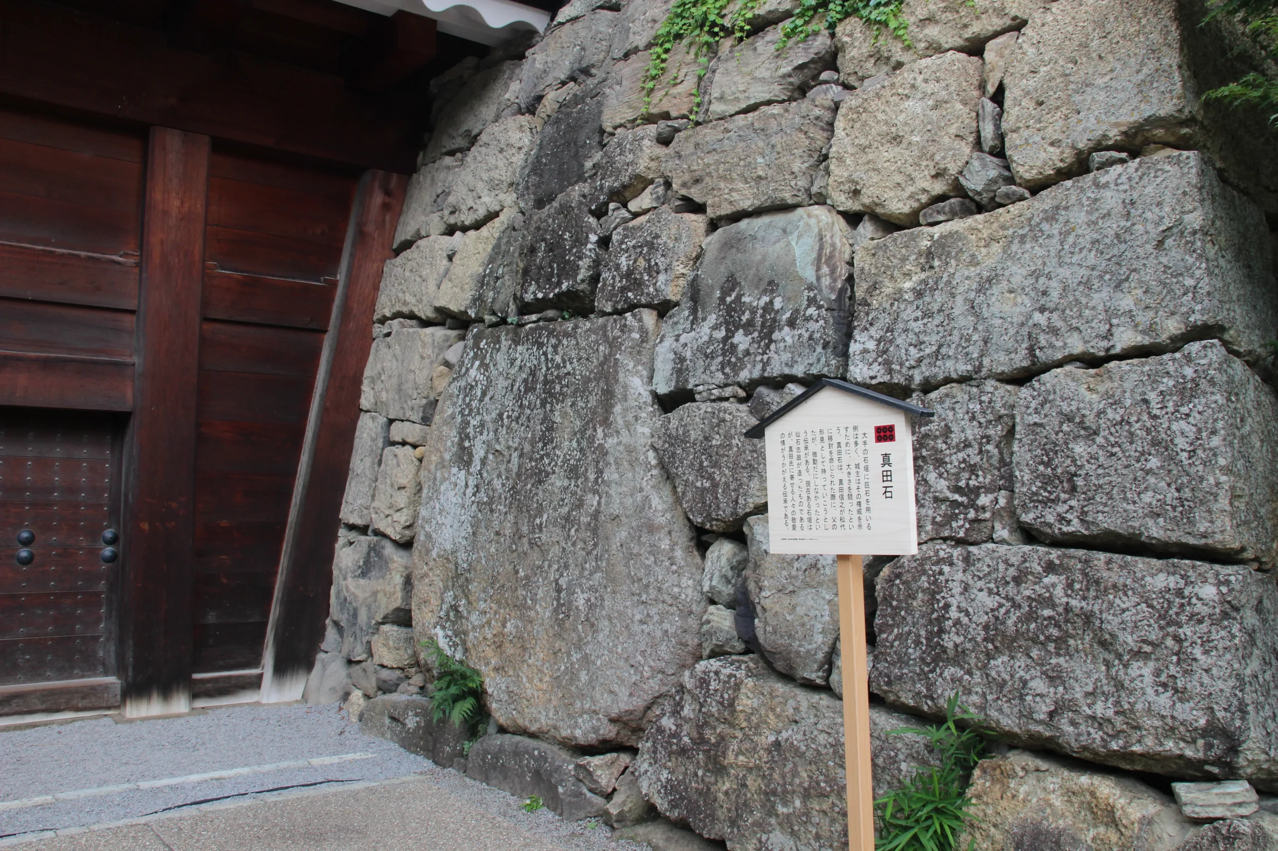 東虎口櫓門の木製扉の脇に堂々と嵌め込まれた巨石「真田石」と解説案内板