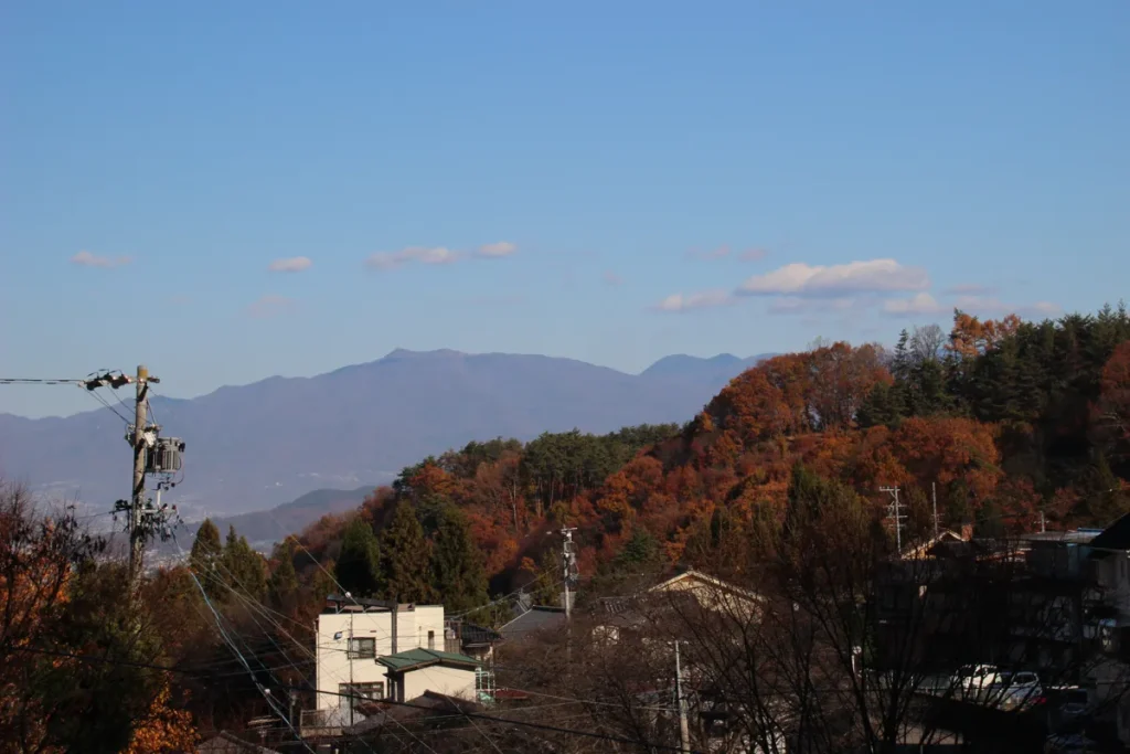 紅葉の木々と遠くの稜線が美しい別所温泉の山里の風景