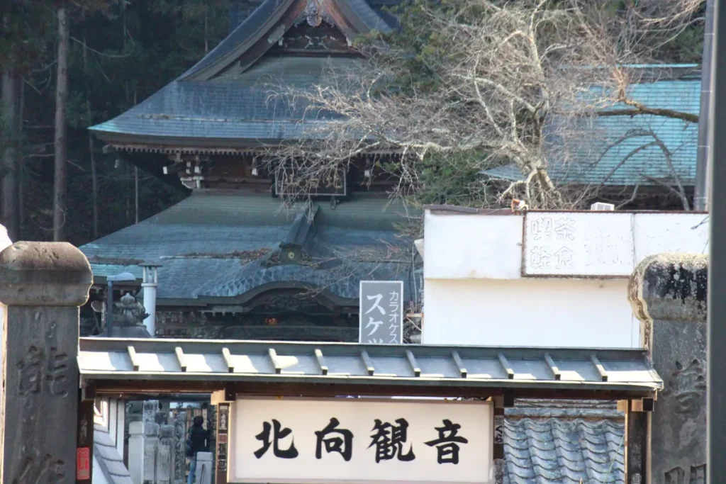 石柱の参道門越しに望む温泉街の街並みと奥に佇む北向観音本堂の屋根