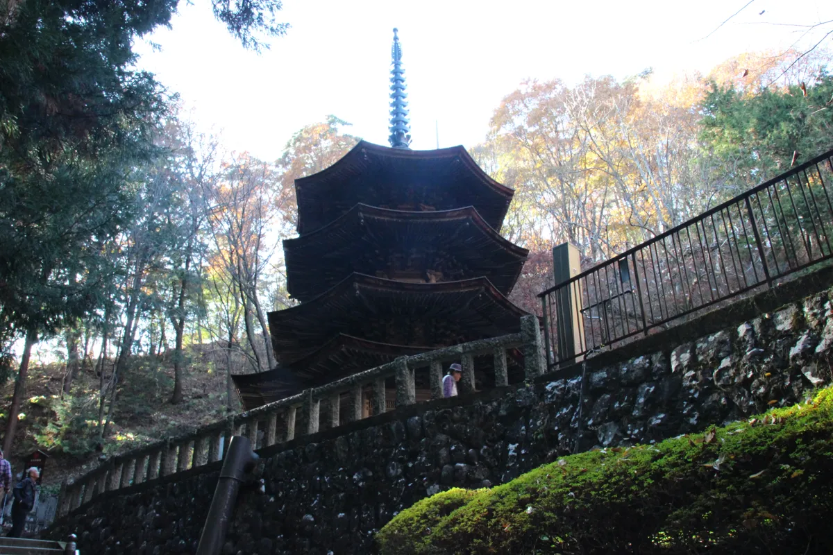 紅葉の木々と石垣を背景に聳え立つ安楽寺の国宝八角三重塔