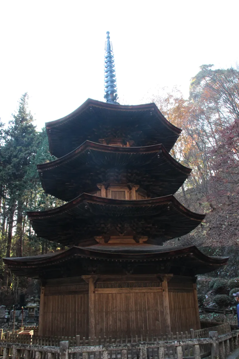 周囲を柵で保護された安楽寺八角三重塔の厳かな縦アングルの全景