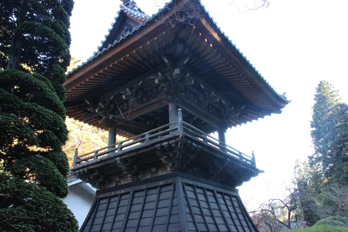 下部が黒い板張りの袴腰で覆われた安楽寺の木造鐘楼の全景