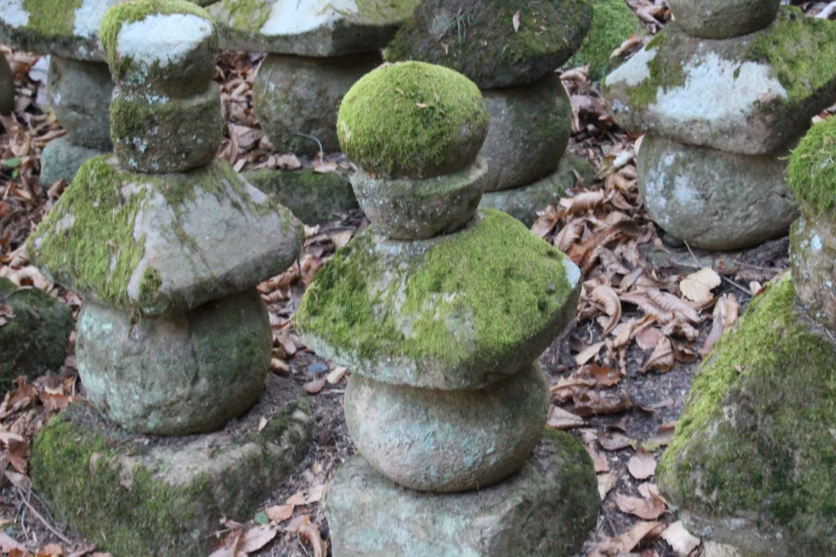 長い歳月を経て美しい緑の苔で覆われた石造の小さな五輪塔のクローズアップ