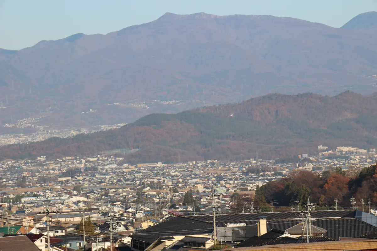 高台から望む上田盆地の広い街並みと奥に聳える壮大な山々の稜線パノラマ