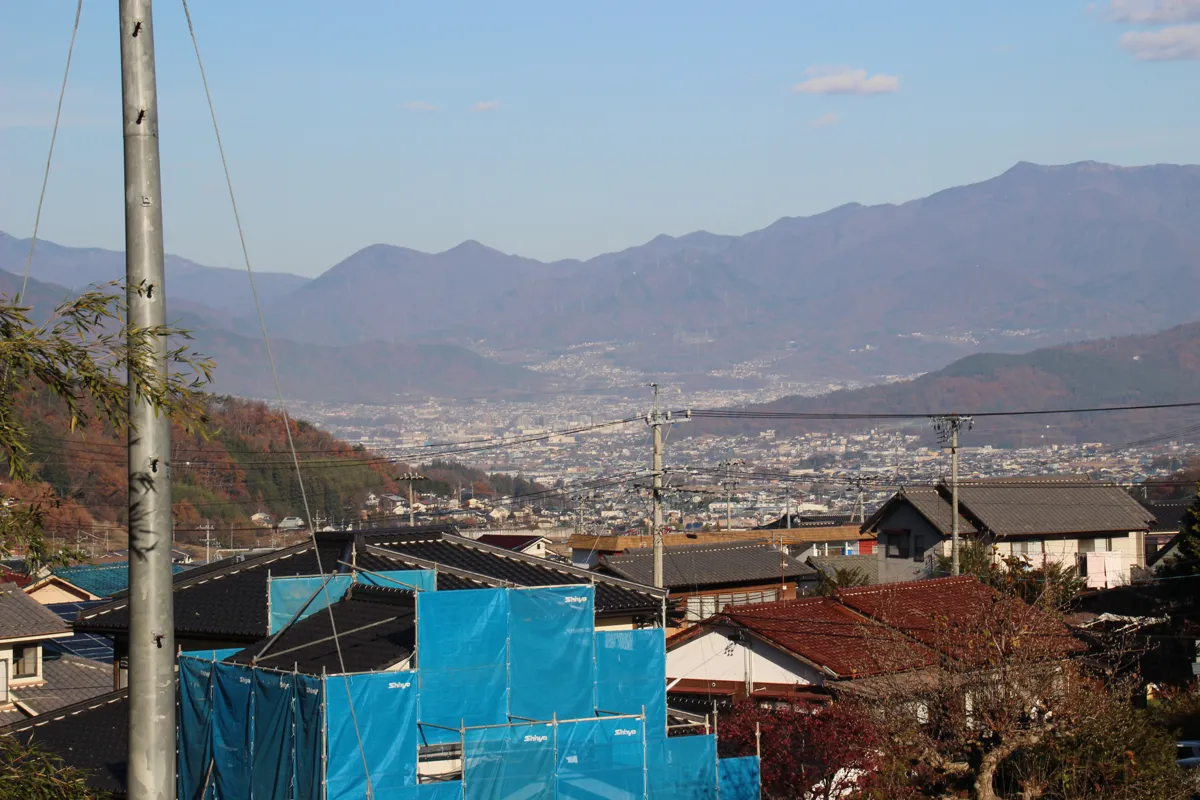 別所温泉の民家の屋根越しに見る、上田盆地と連なる美しい山々の遠景