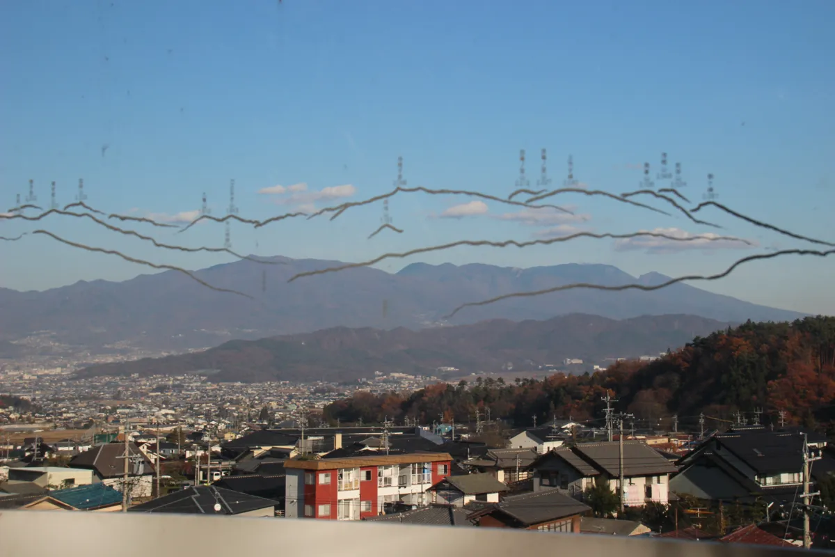 アクリル製眺望案内板越しに望む、塩田平の街並みと遠くの山々のパノラマ