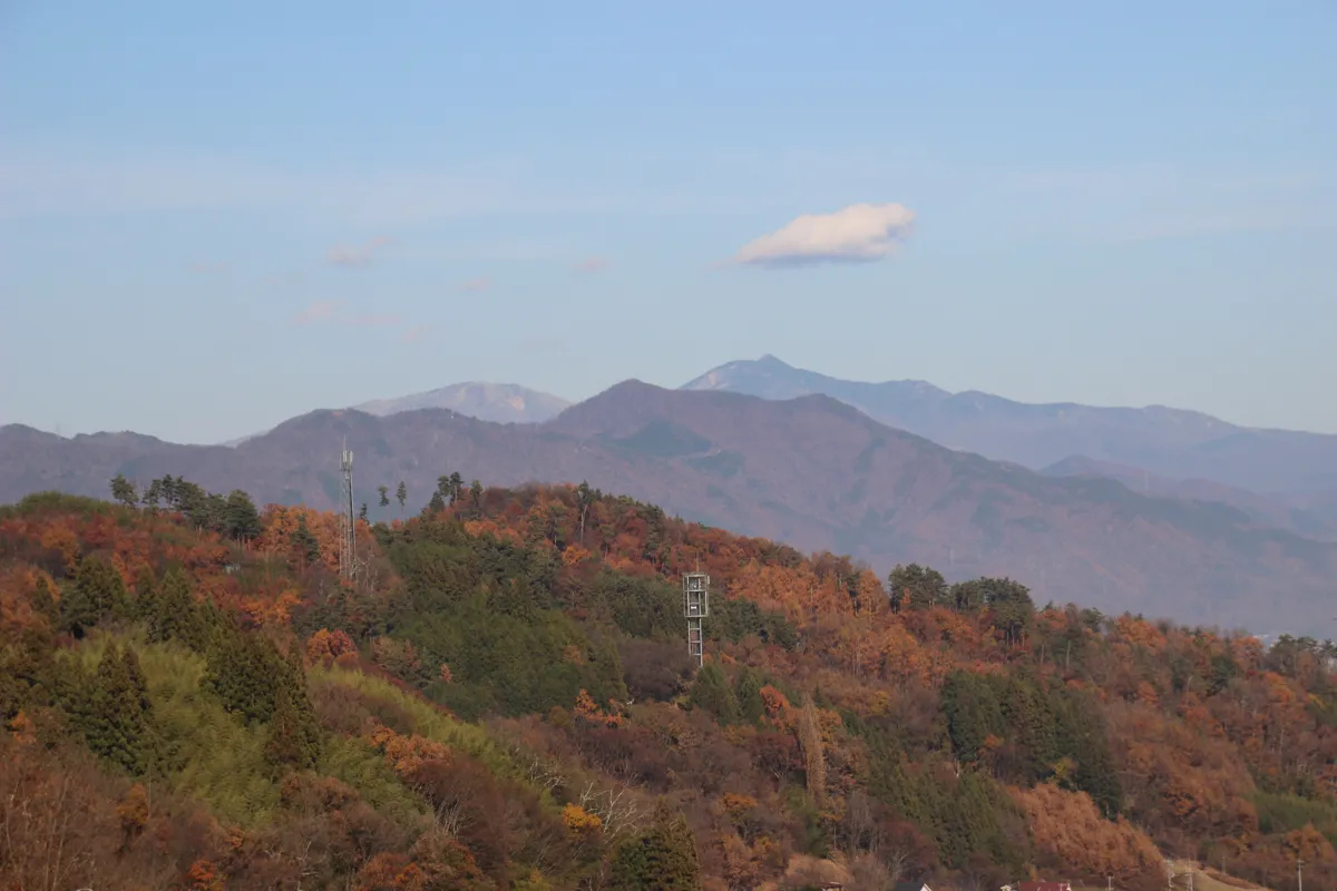 展望台から見渡す、紅葉に染まる里山の斜面と遠方に聳える信州の山々
