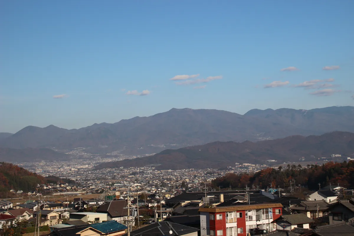 別所温泉街の民家が密集する様子と、その背後に大きく広がる信州の山並み