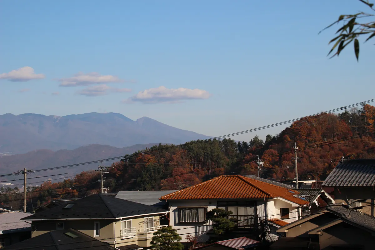 別所温泉街の民家と、その背後に広がるなだらかで美しい信州の山岳遠景