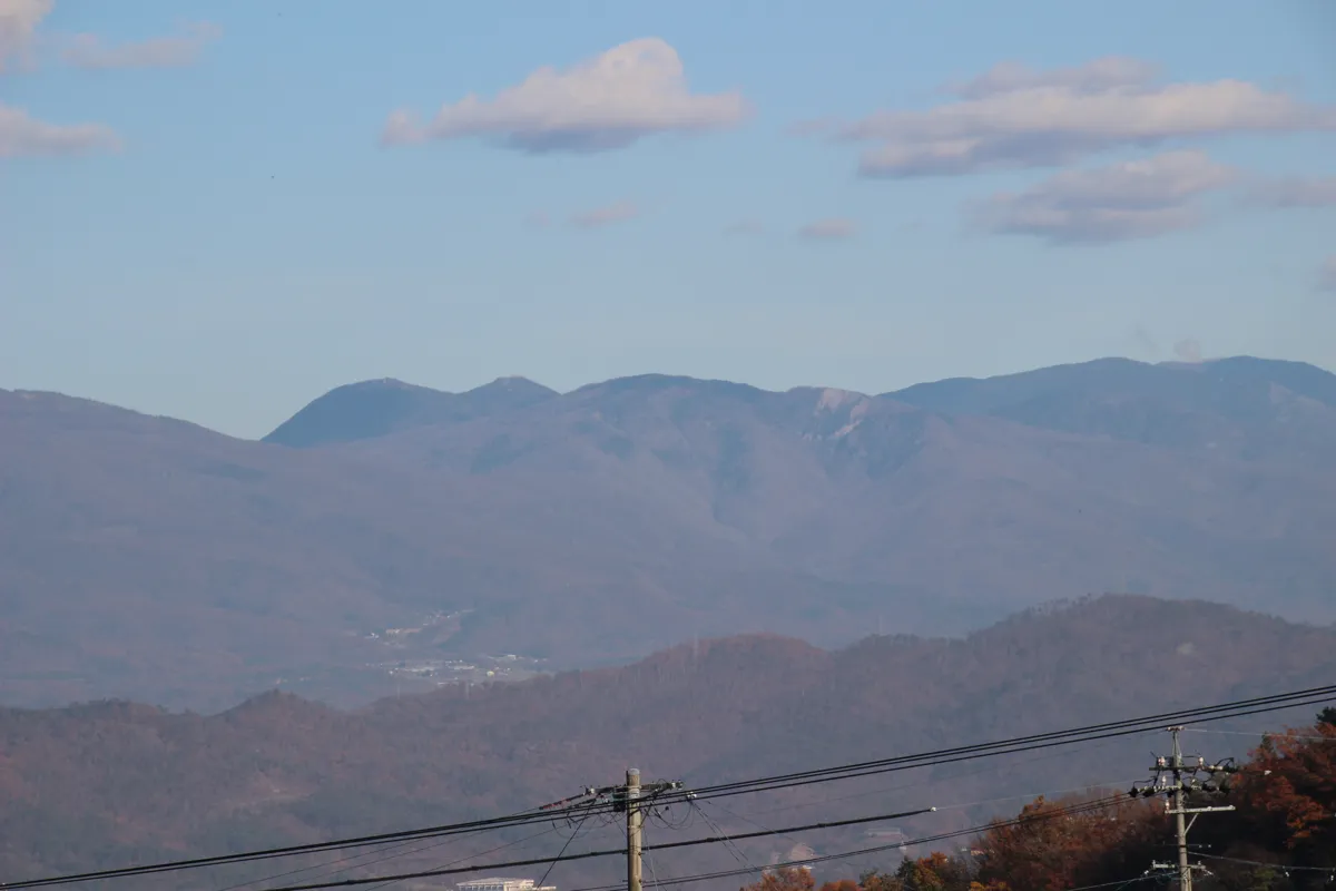 秋の澄んだ青空と白い雲、その下に横たわるなだらかな山脈のパノラマ