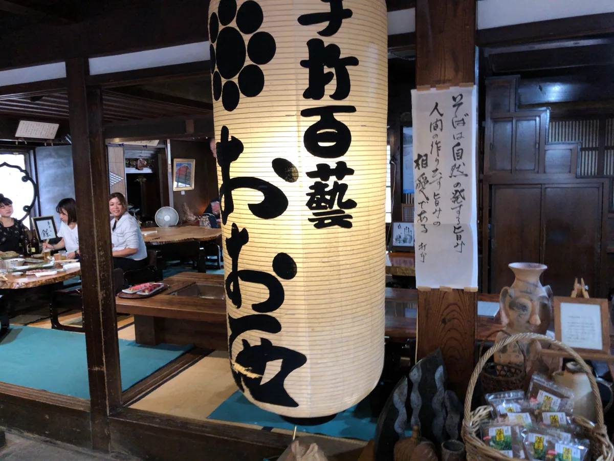 信州の古民家風の落ち着いた空間に吊るされた「十割百藝 おおにし」と書かれた風格ある大きな白提灯の景観