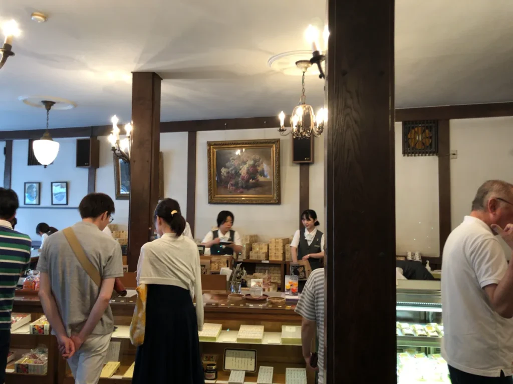 多くの観光客で賑わう飯島商店の販売カウンターと、背後の棚に綺麗に並べられたみすず飴や果物ジャムの箱