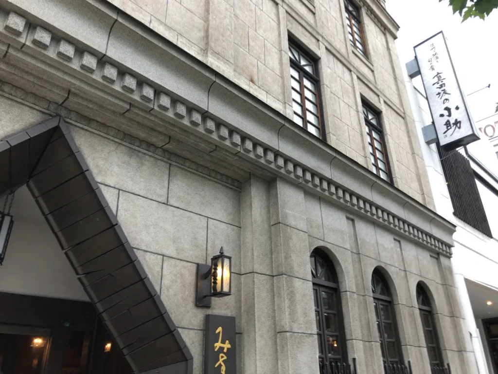 石造りの重厚な外壁と格子付きのアーチ窓が特徴的な飯島商店の歴史的洋館建築の2階・3階部分の外観